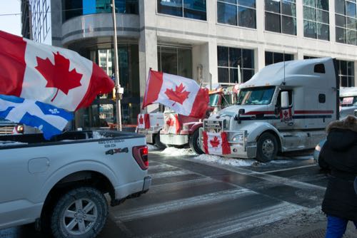 A picture of transport trucks and pickup trucks flying Canadian and Quebec flags.